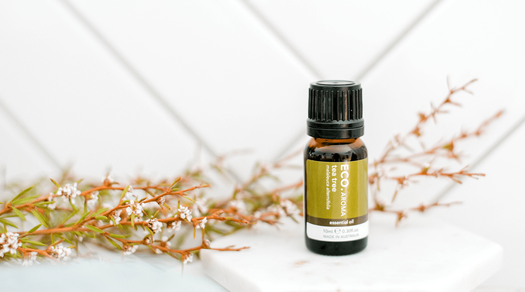 ECO.AROMA tea tree essential oil bottle with tea tree sprigs
