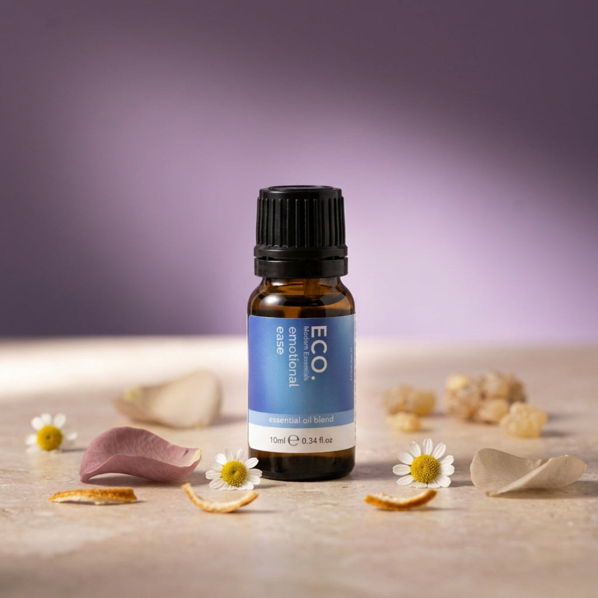 Bottle of ECO essential oil blend on a wooden surface with flowers and petals.