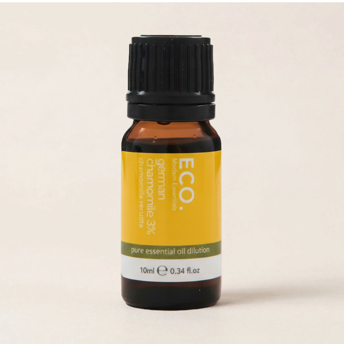 Bottle of ECO German Chamomile essential oil on a beige background