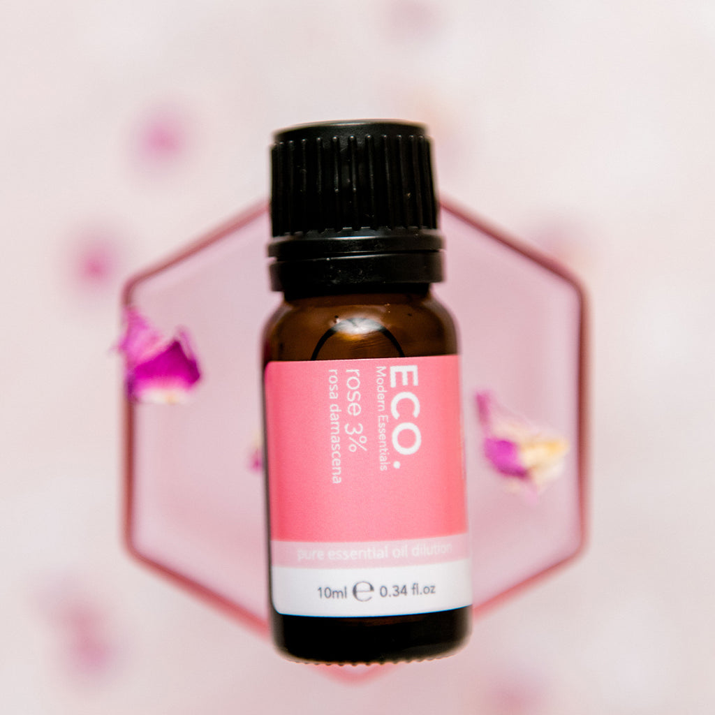 Rose essential oil bottle with rose flower petals in the background