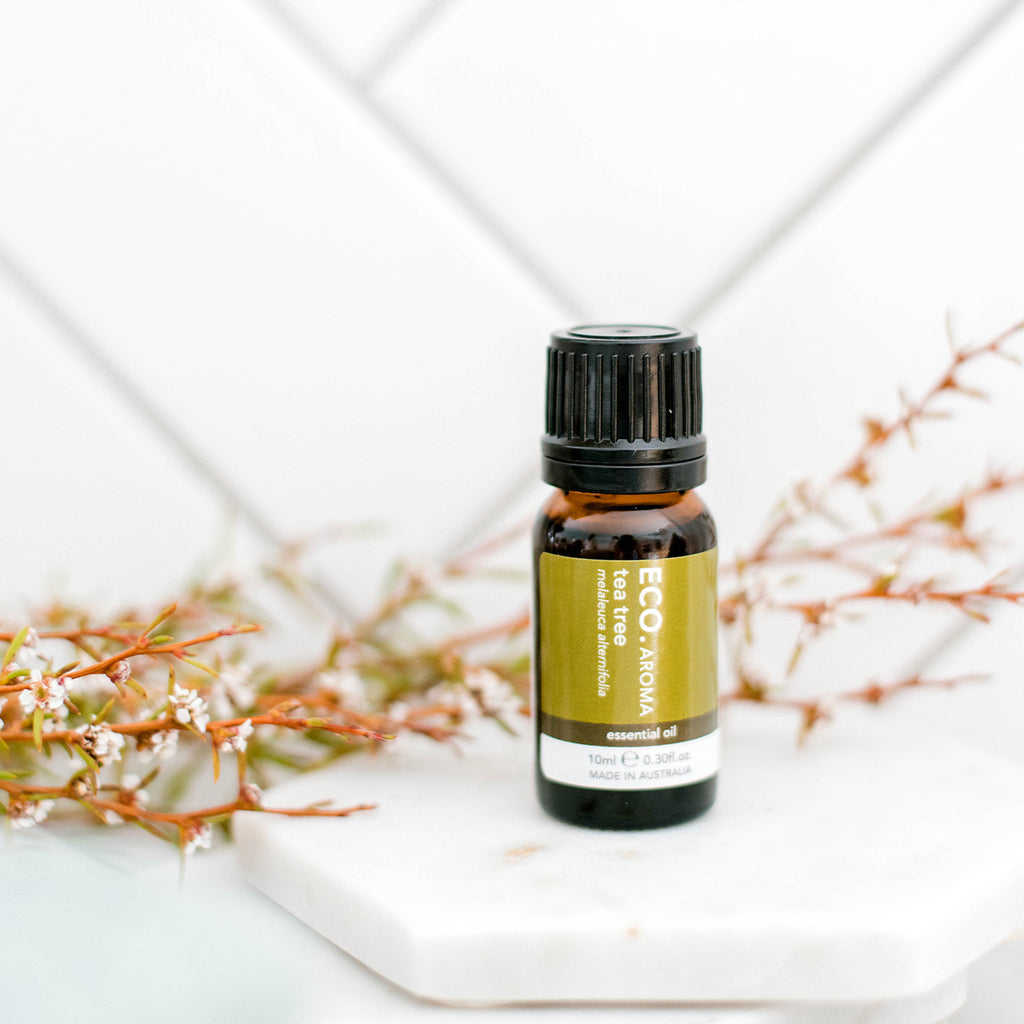 Pure Tea Tree essential oil with flowers in the background